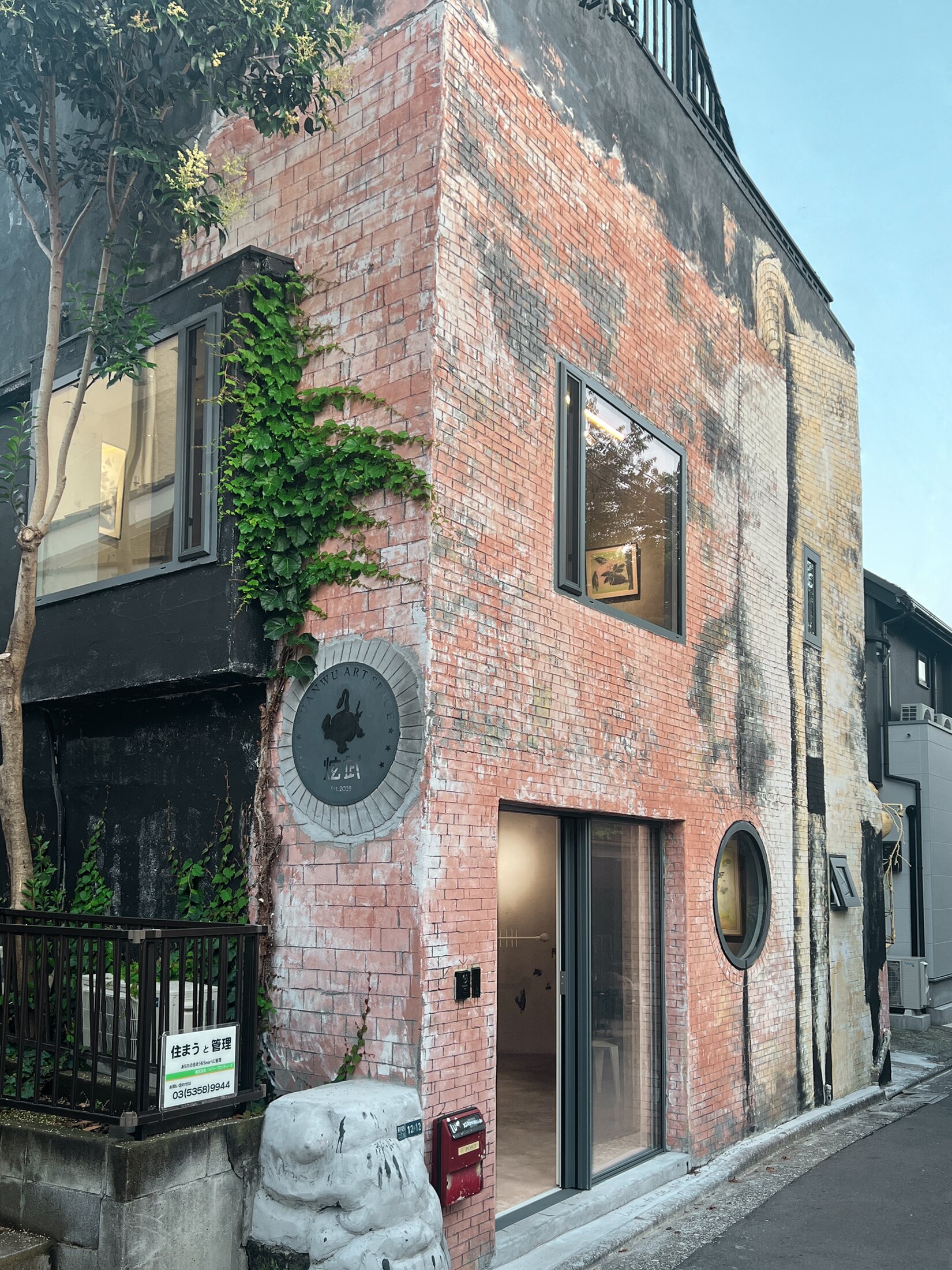 Xuanwu Art Space — ivy-clad side wall with the round Xuanwu plaque and stone guardian